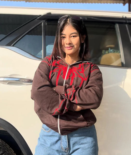 Woman wearing brown Spider-Man hoodie with red graphic and blue jeans outdoors