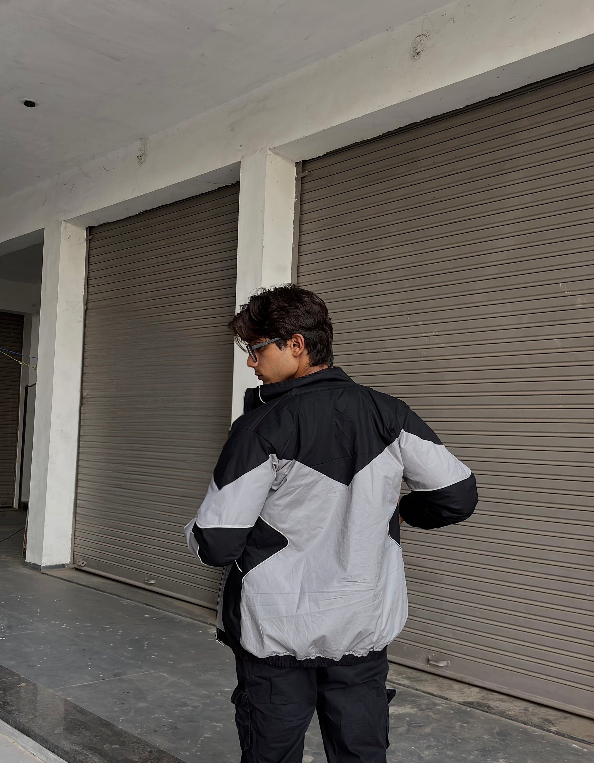 Back profile of the flash-reactive windbreaker designed for night-time streetwear visibility.