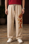 Beige Chinese dragon baggy pants for unisex with red and gold 3D embroidery by Suspended Clothing.
