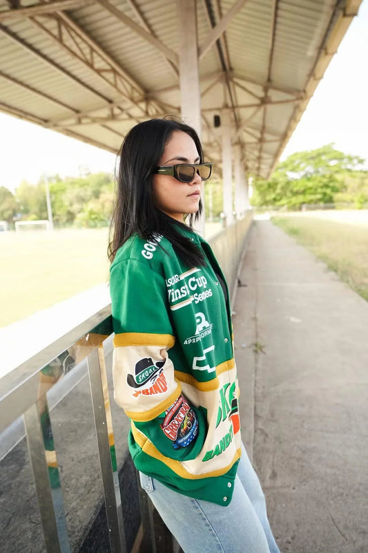 Woman in green vintage racing patch jacket with zipper, standing outdoors in streetwear style