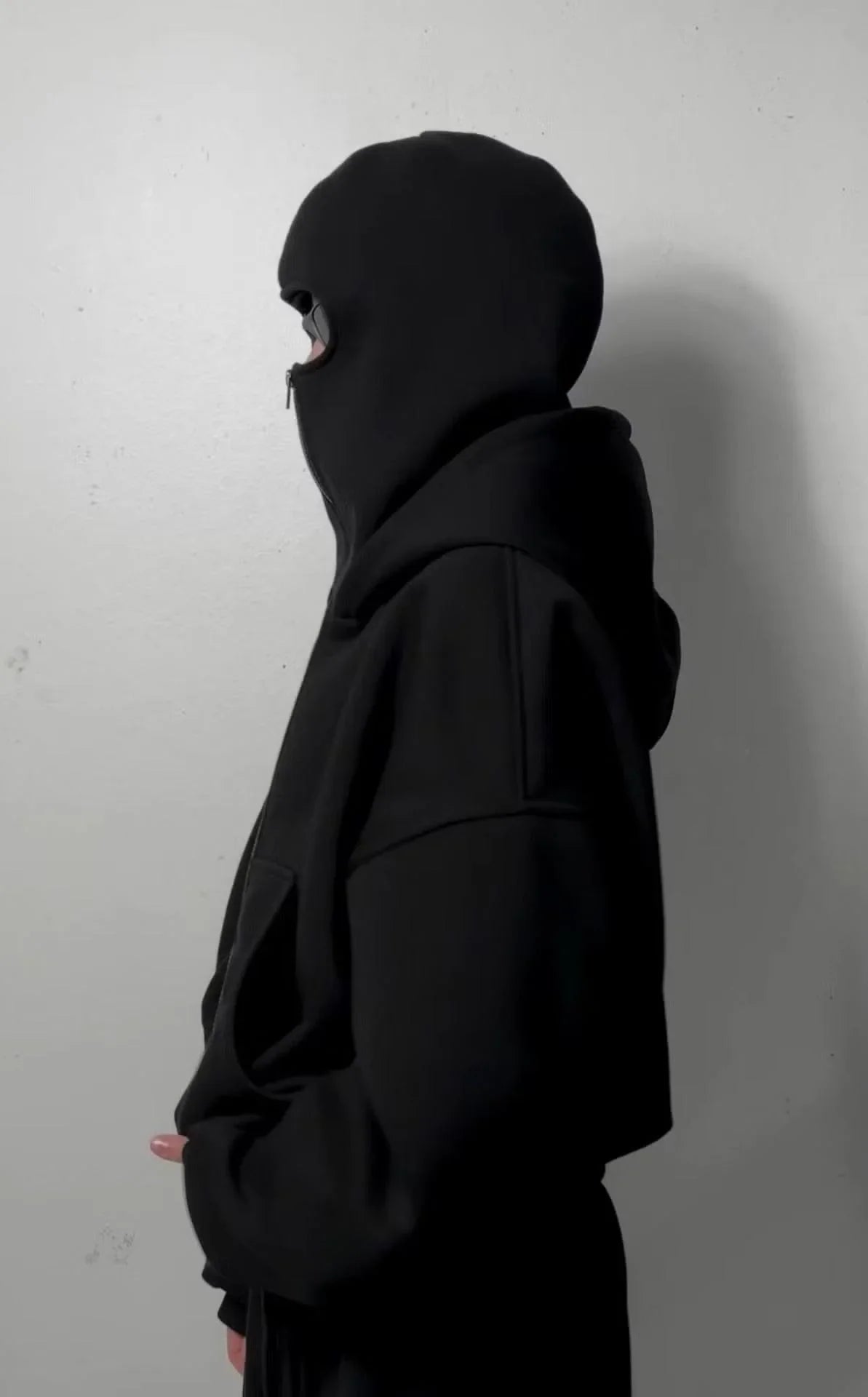 Side view of a jet black balaclava hoodie made from heavyweight cotton, urban streetwear style
