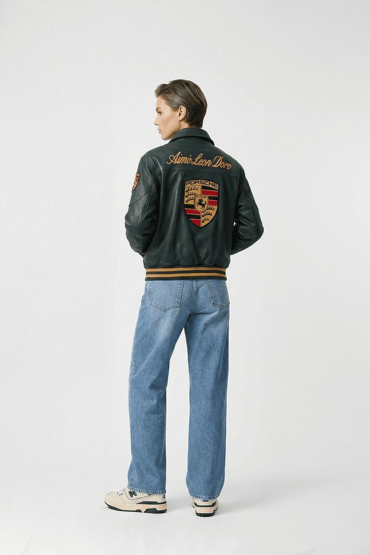 Person wearing a green jacket with a logo on the back, standing against a white background