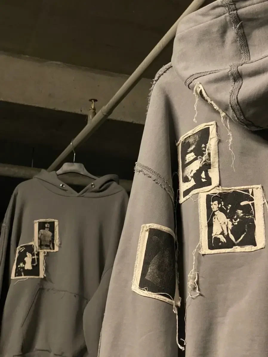 Gray streetwear hoodies with raw hem and vintage photo patches, hanging on a rack