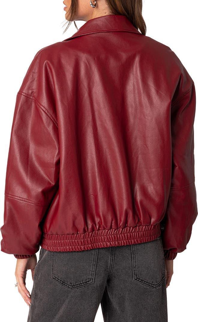 Woman wearing a burgundy faux leather jacket with black wide-leg jeans, back view