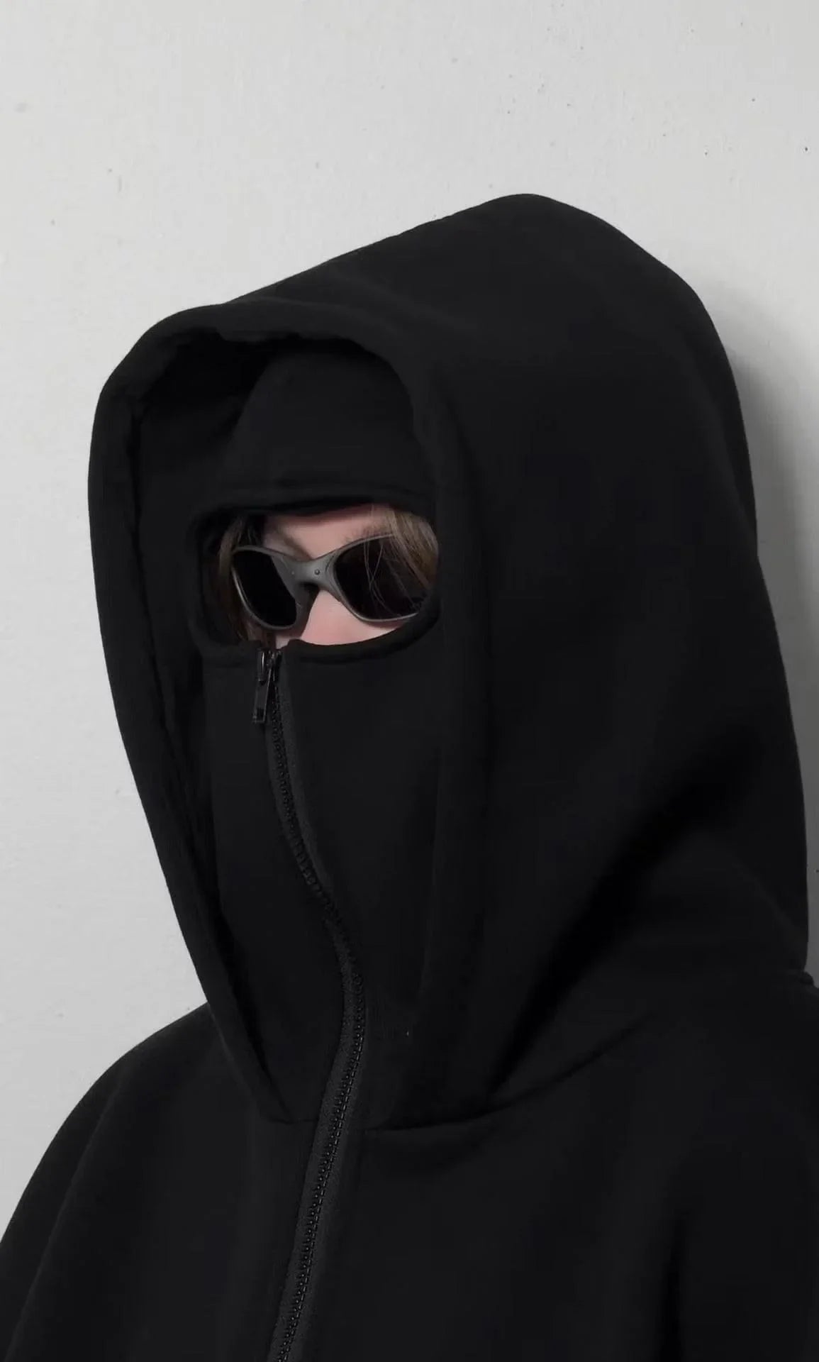 Person wearing black balaclava hoodie with integrated mask, sunglasses, and heavyweight fleece.