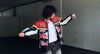 Man in navy Red Bull racing leather jacket with boxy streetwear silhouette posing outdoors
