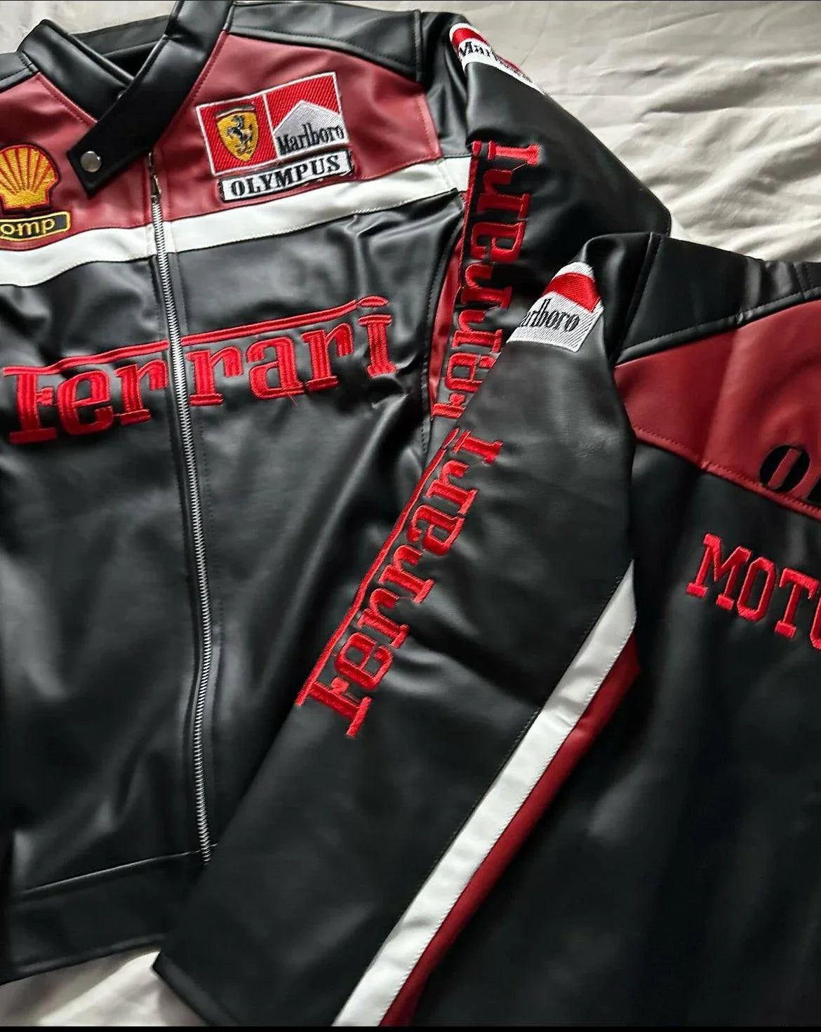 Black and burgundy biker jacket with Ferrari logos, Olympus patch, and racing-inspired details.